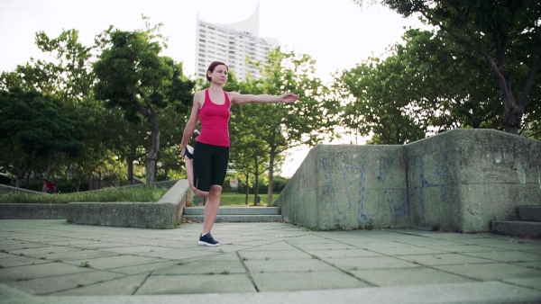 Young woman doing exercise outdoors in city, stretching. Slow motion.