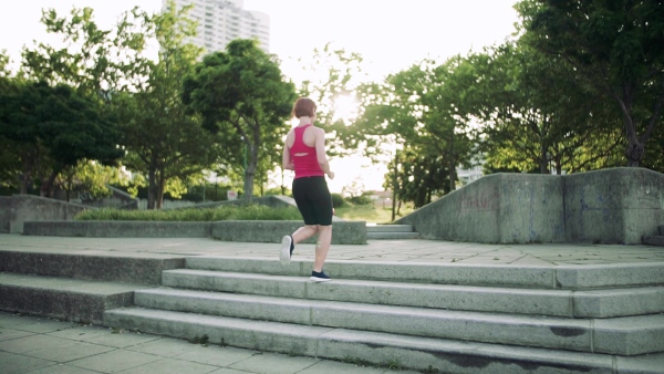 Young woman doing exercise on stairs outdoors in city. Slow motion.