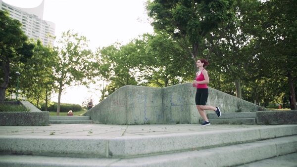 Young woman doing exercise outdoors in city, running. Slow motion.