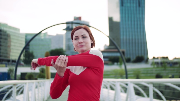 A young woman doing exercise on bridge outdoors in city, stretching.