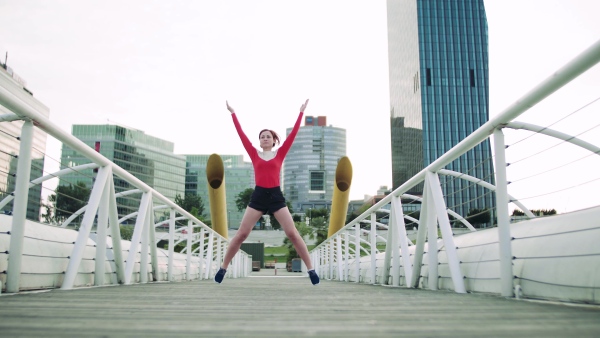 A young woman doing exercise on bridge outdoors in city.