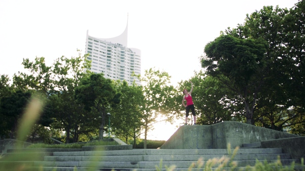 Full length portrait of young woman doing exercise outdoors in city, stretching.