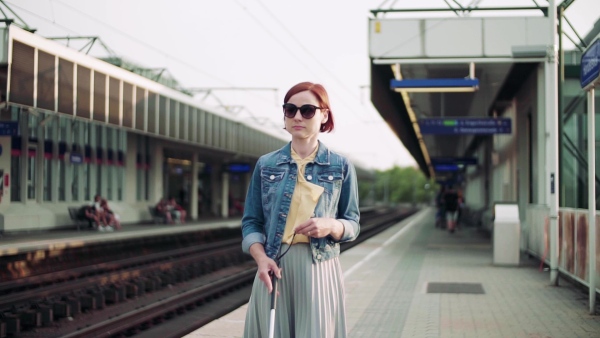 Young blind woman commuter with white cane walking outdoors in city. Slow motion.