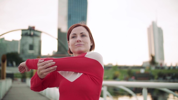 Young woman doing exercise on bridge outdoors in city, stretching. Slow motion.