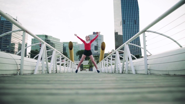 Young woman doing exercise on bridge outdoors in city. Slow motion.