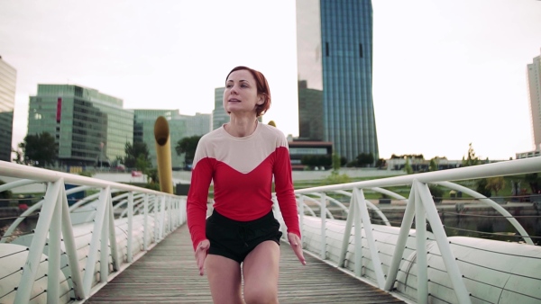 Young woman doing exercise on bridge outdoors in city. Slow motion.