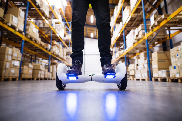 Unrecognizable man warehouse worker on a hoverboard.