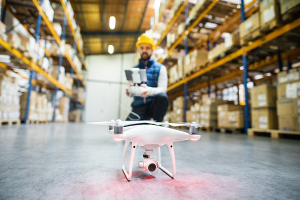 Man or a worker with drone standing in a warehouse.