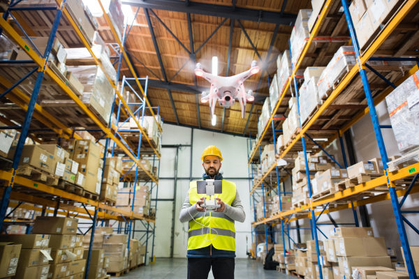 Man or a worker with drone standing in a warehouse.