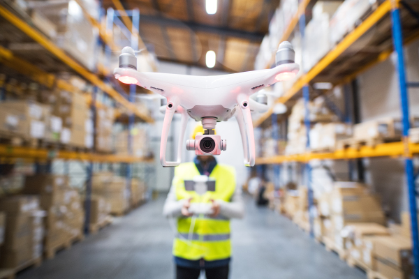 Man or a worker with drone standing in a warehouse.