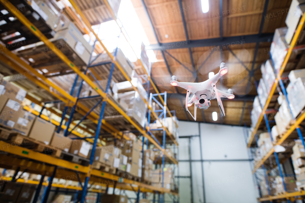 White drone flying inside the big warehouse.