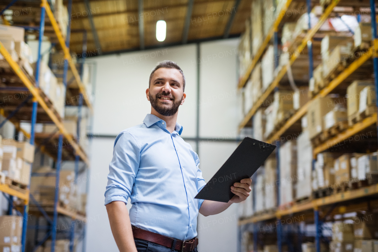 Portrait of a male warehouse worker or a supervisor holding notes.