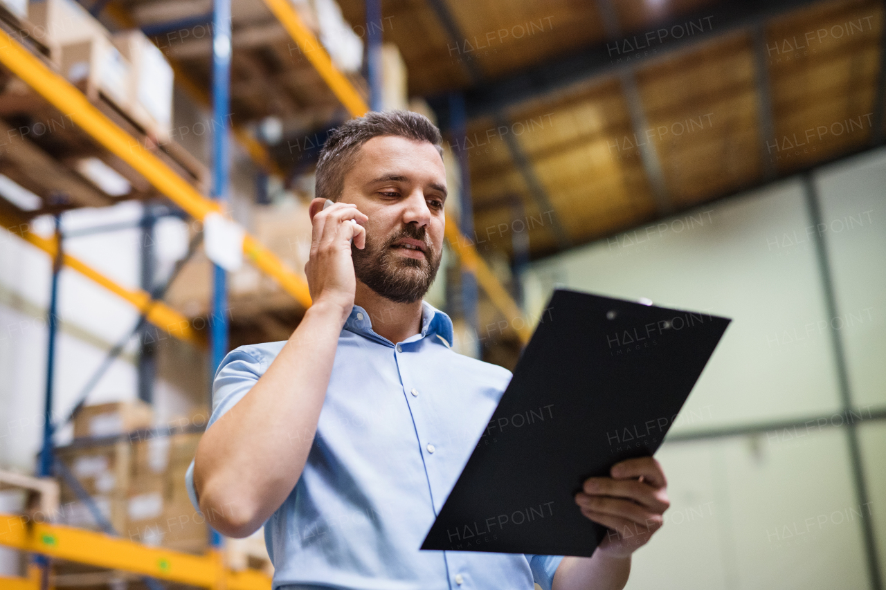 Warehouse worker or supervisor with a smartphone, making a phone call.