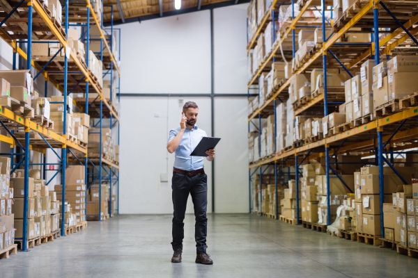 Warehouse worker or supervisor with a smartphone, making a phone call.