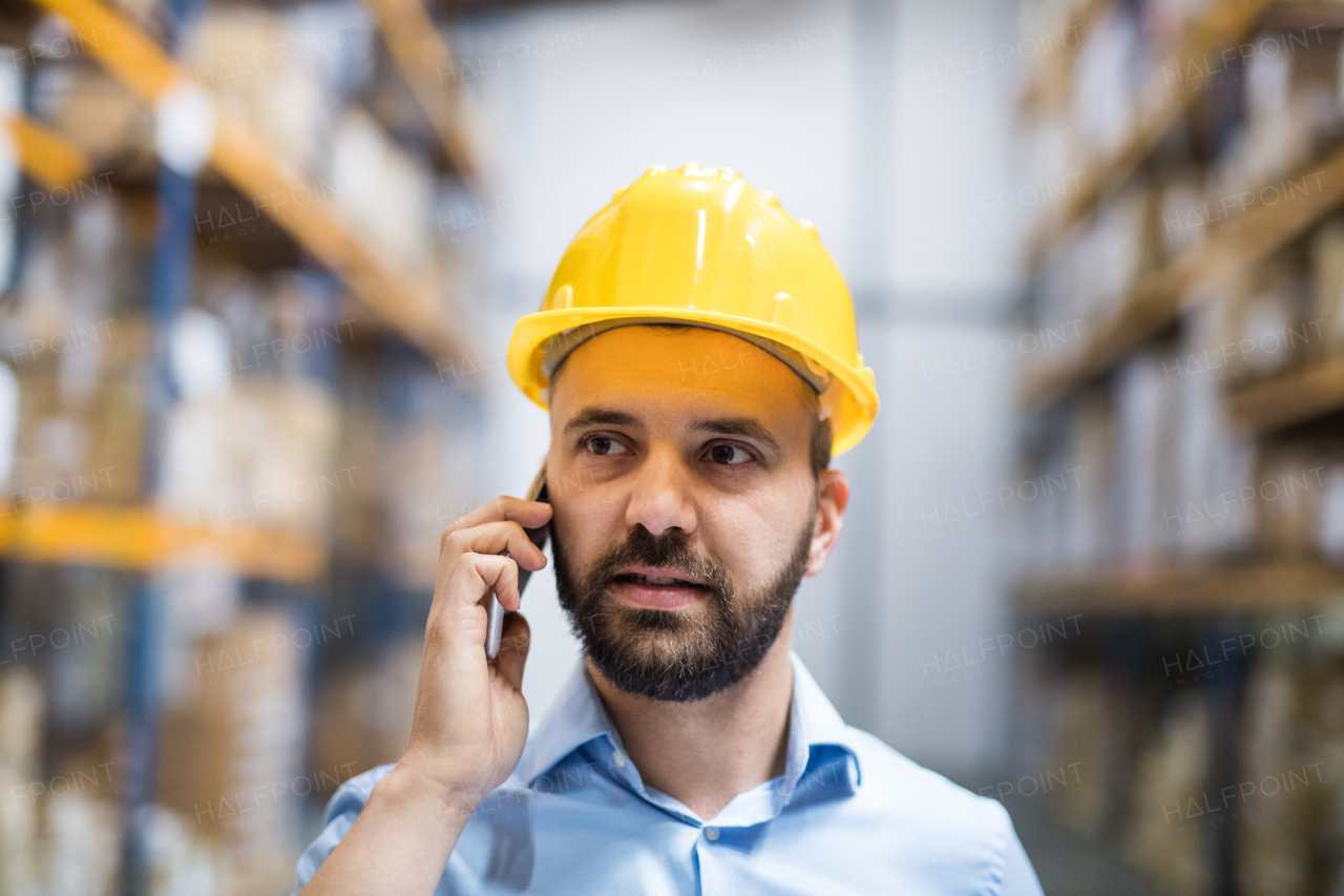 Warehouse worker or supervisor with a smartphone, making a phone call.