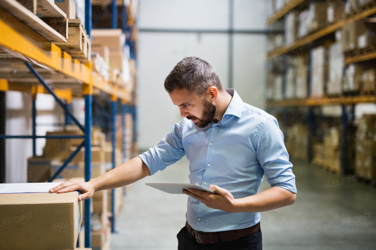 Handsome man warehouse worker with a tablet.