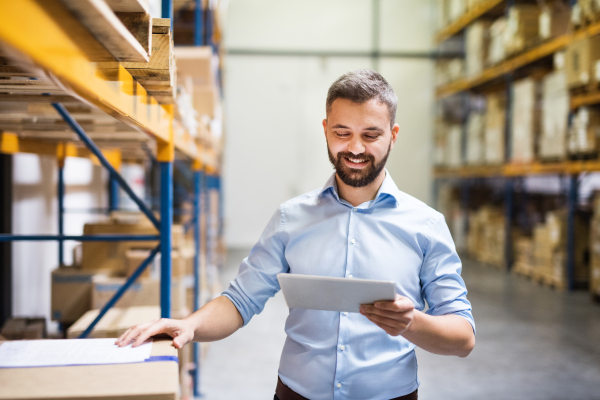 Handsome man warehouse worker with a tablet.