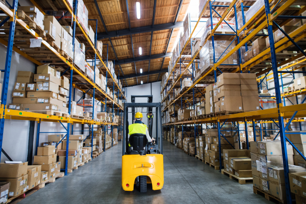 Man forklift driver working in a warehouse. Rear view.