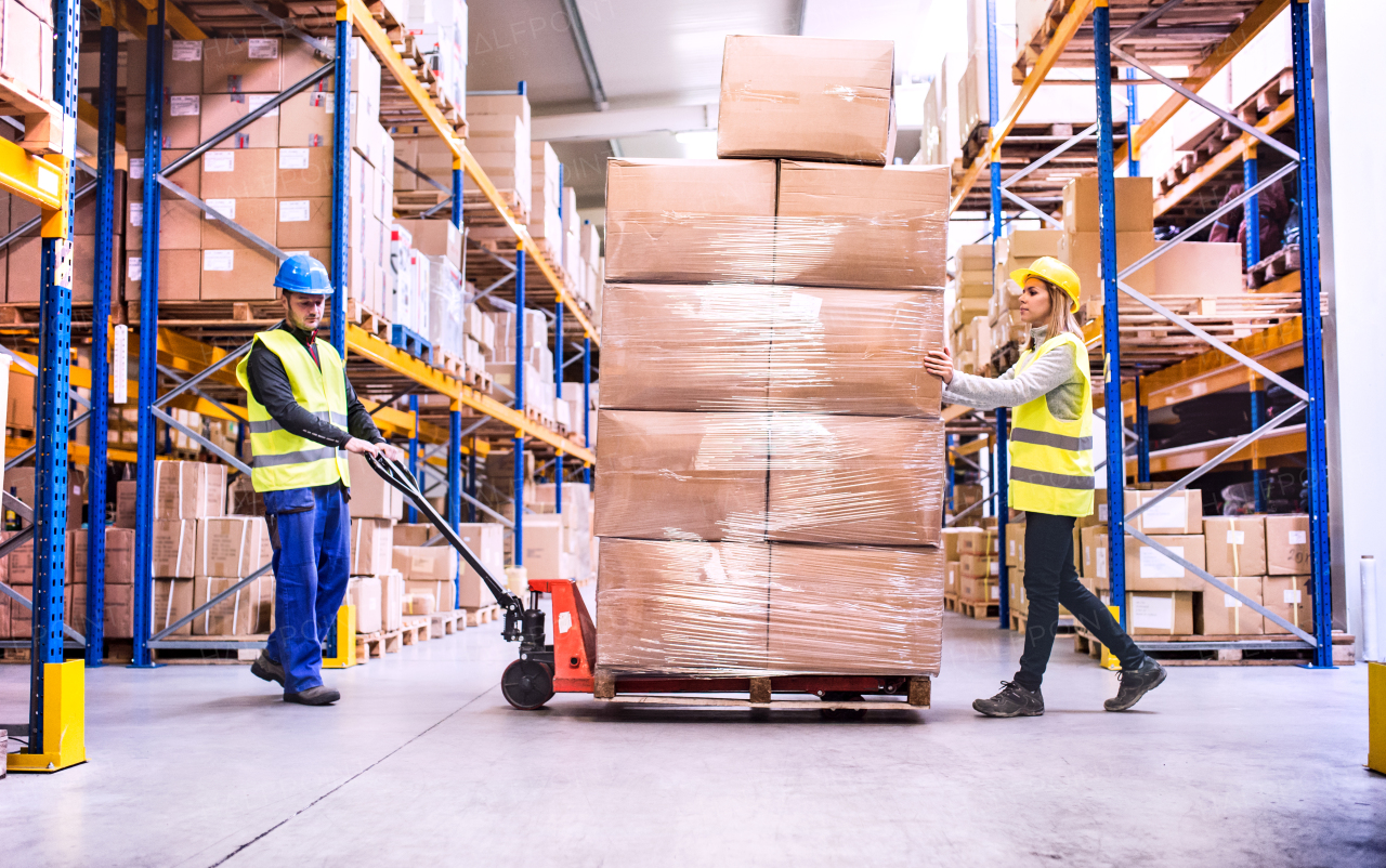 Young warehouse workers pulling a pallet truck with boxes.