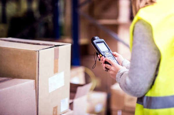 Unrecognizable warehouse woman worker or supervisor with barcode scanner. A mobile handheld PC with barcode scanner.