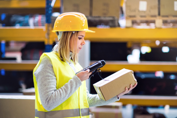 Warehouse woman worker or supervisor with barcode scanner. A mobile handheld PC with barcode scanner.