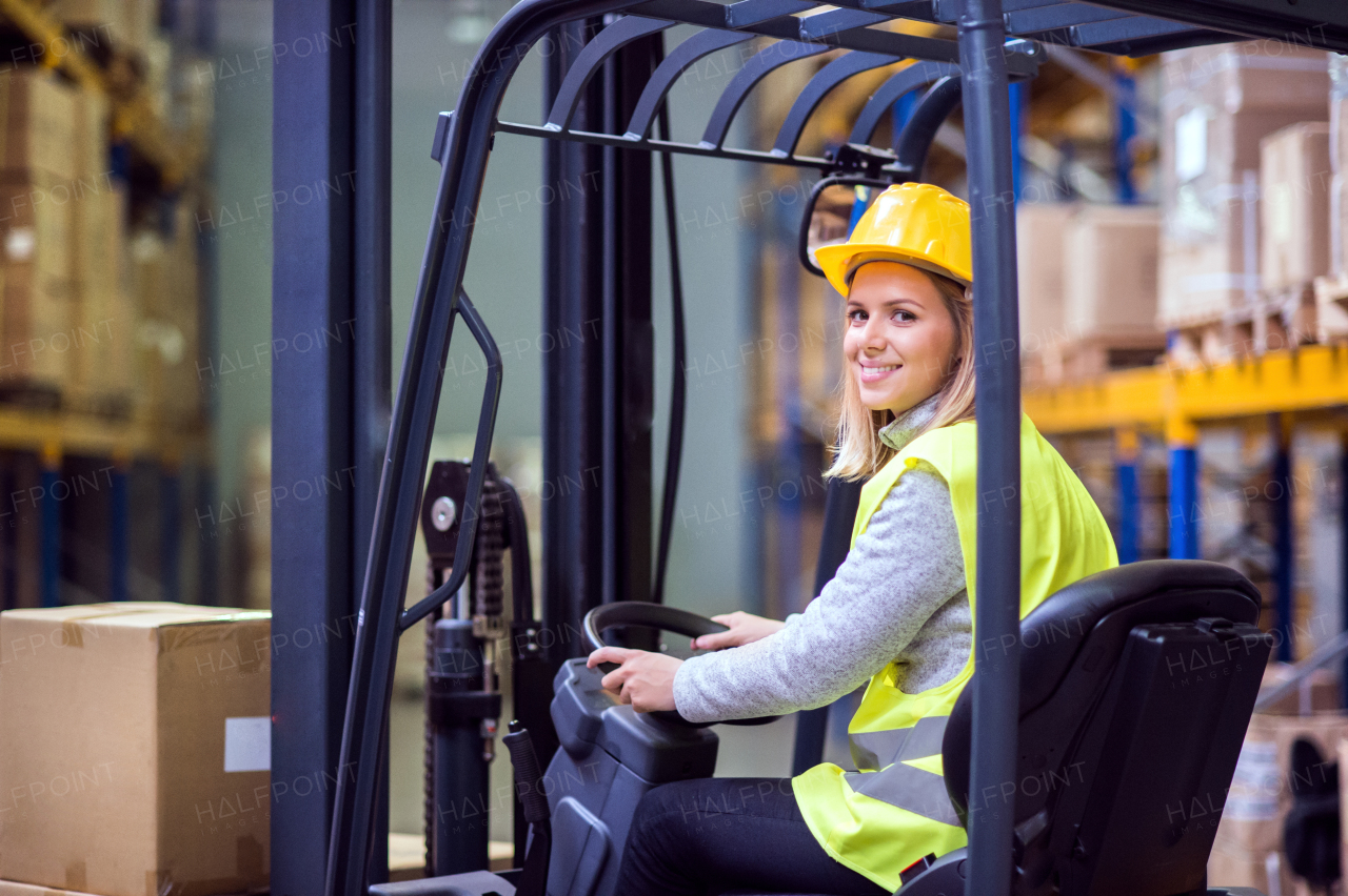 Beautiful young woman warehouse worker with forklift.