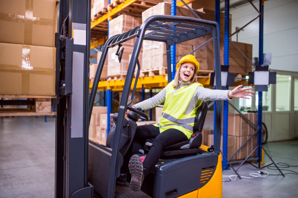 Beautiful young woman warehouse worker with forklift.