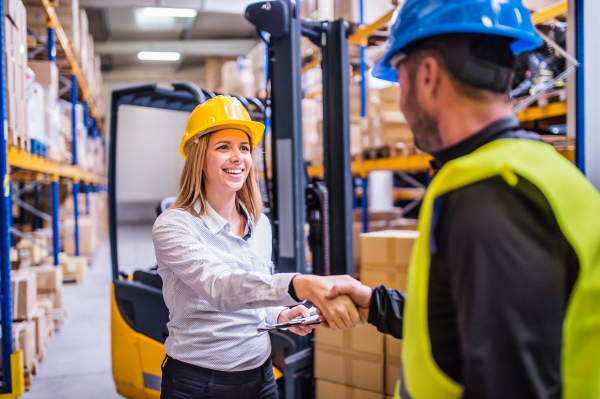 Young workers working together in a warehouse, shaking hands.