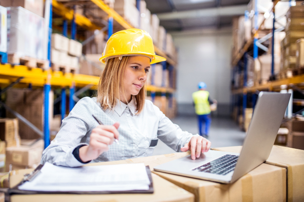 Young workers with laptop working in a warehouse.