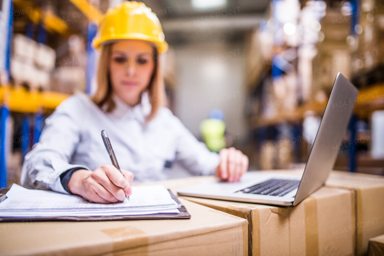 Young worker with laptop working in a warehouse.