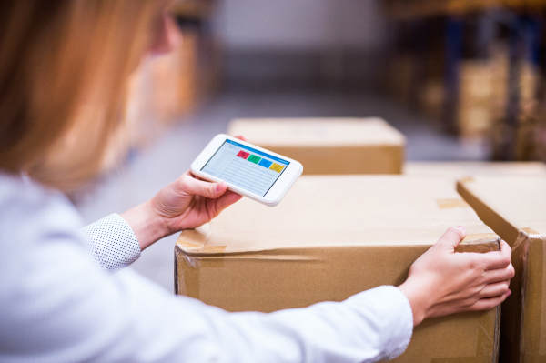 Young woman warehouse worker or supervisor with smartphone.