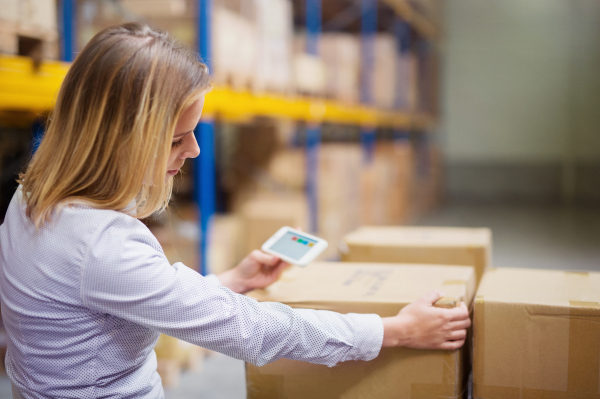 Young woman warehouse worker or supervisor with smartphone.