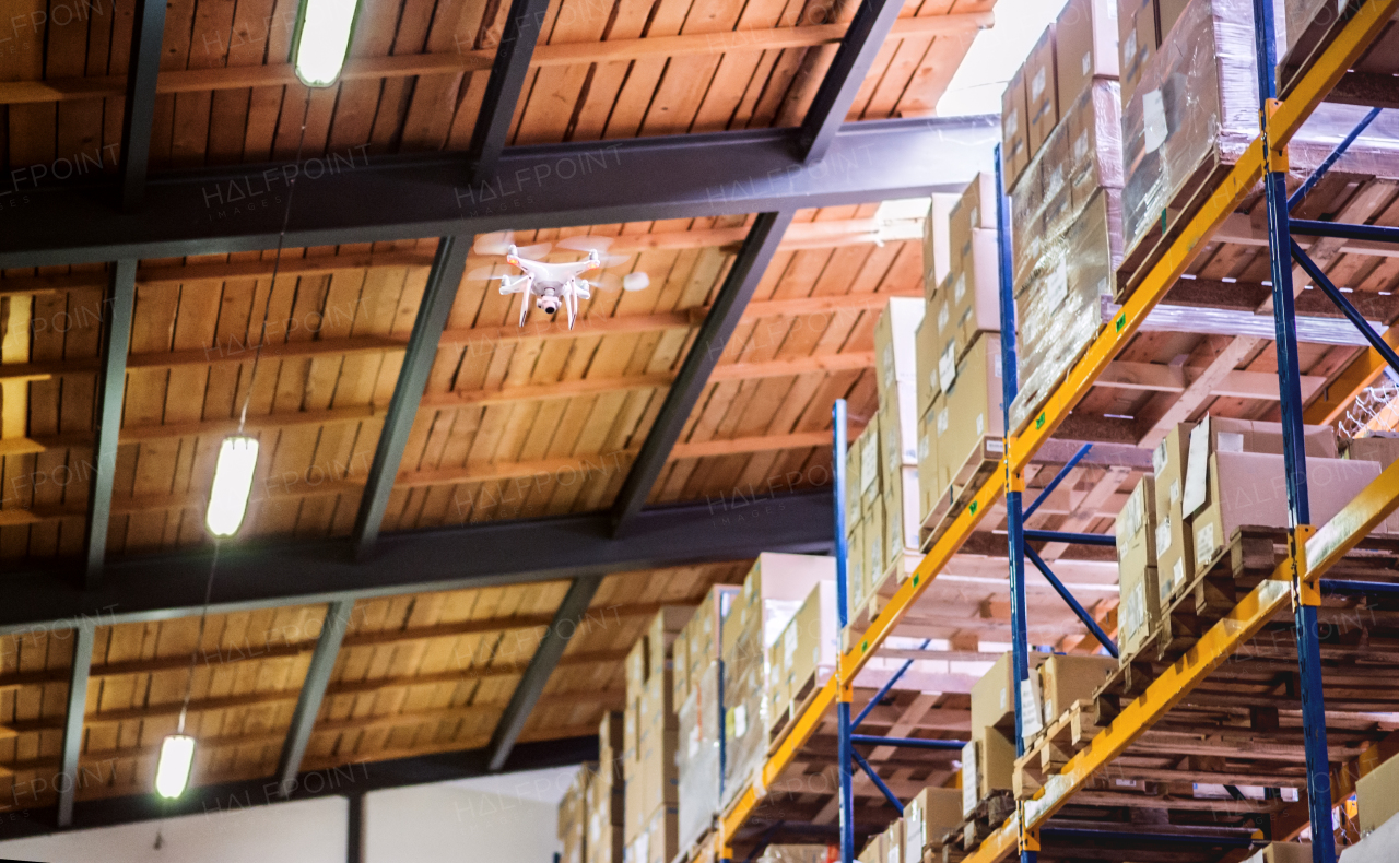 White drone flying inside the warehouse, under a wooden roof.