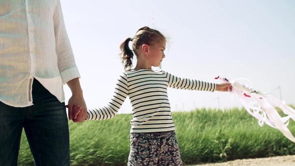 Unrecognizable father with small daughter standing on wind farm. Slow motion.