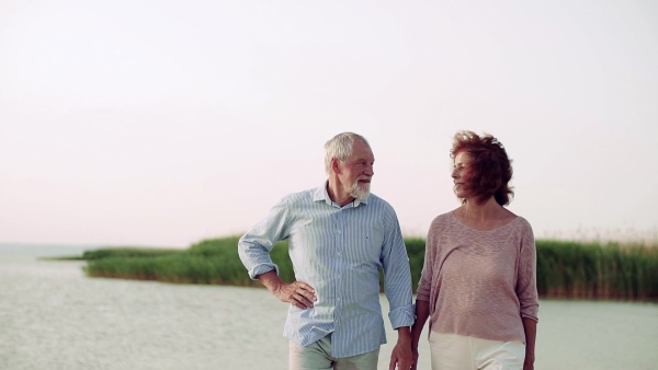 A senior couple on a holiday on a walk by the lake. Slow motion.