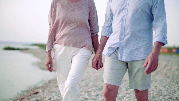 A midsection of senior couple on a holiday on a walk by the lake. Slow motion.