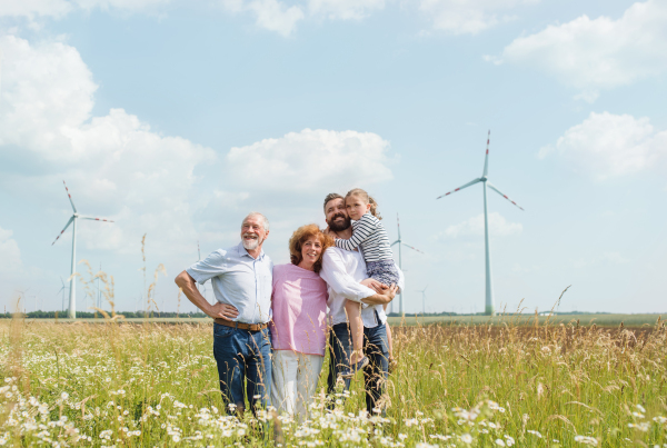 A front view of multigeneration family standing on field on wind farm.