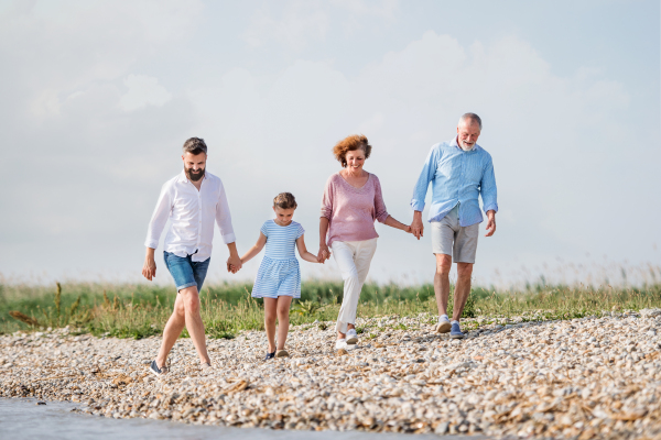 A multigeneration family on a holiday walking by the lake, holding hands.