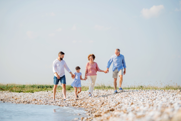 A multigeneration family on a holiday walking by the lake, holding hands.