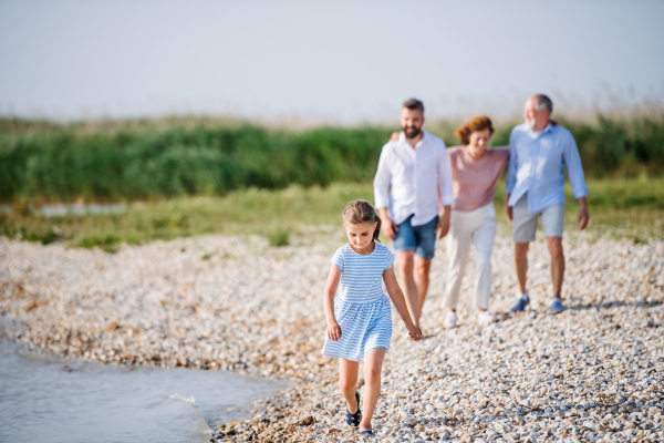 A multigeneration family on a holiday walking by the lake, holding hands.