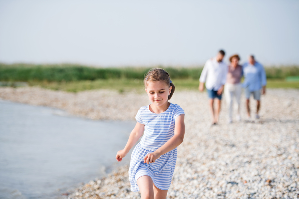 A small girl with family on a holiday walking by the lake, holding hands.