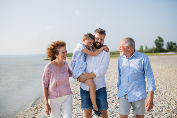 A multigeneration family on a holiday walking by the lake, holding hands.