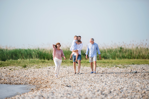 A multigeneration family on a holiday walking by the lake, holding hands.