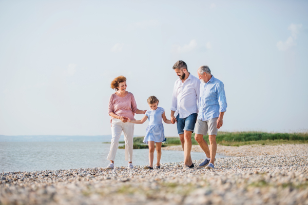 A multigeneration family on a holiday walking by the lake, holding hands.