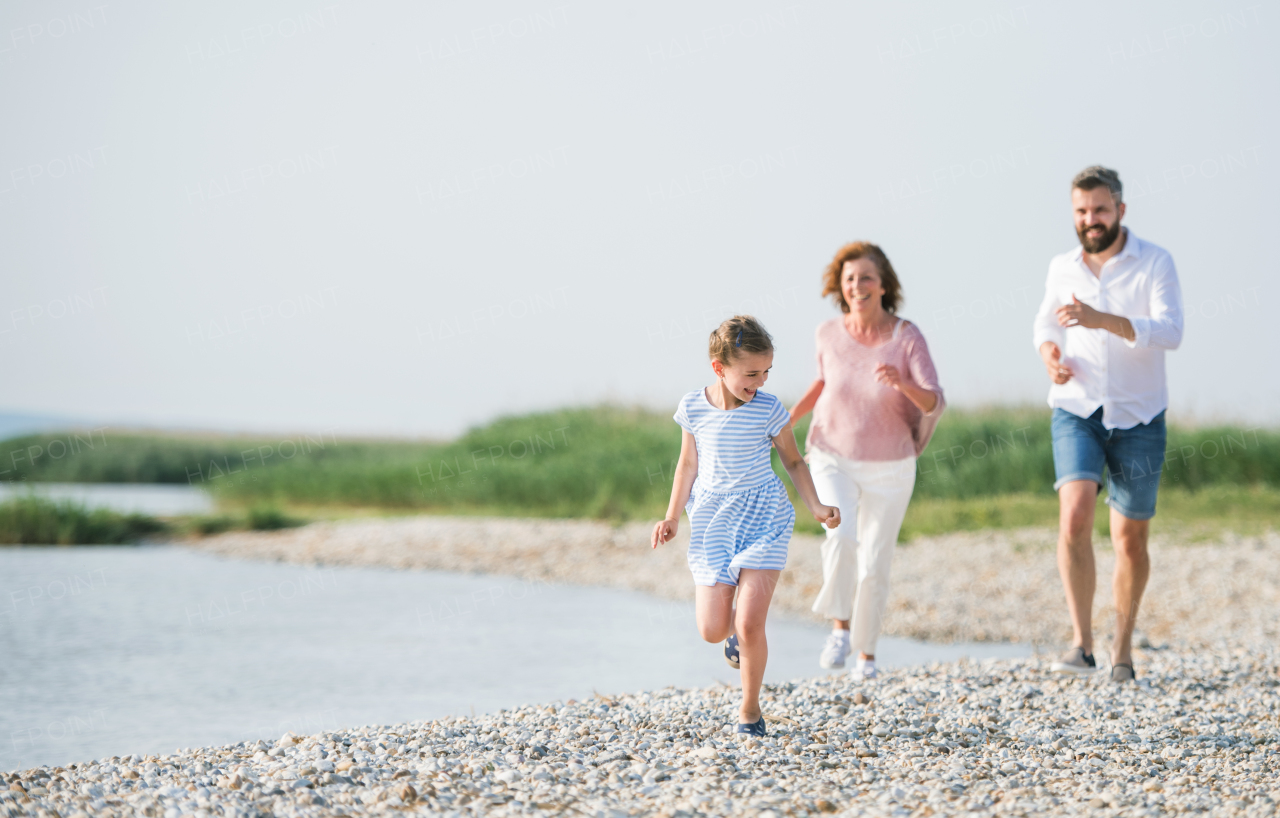 A multigeneration family on a holiday walking by the lake, running.