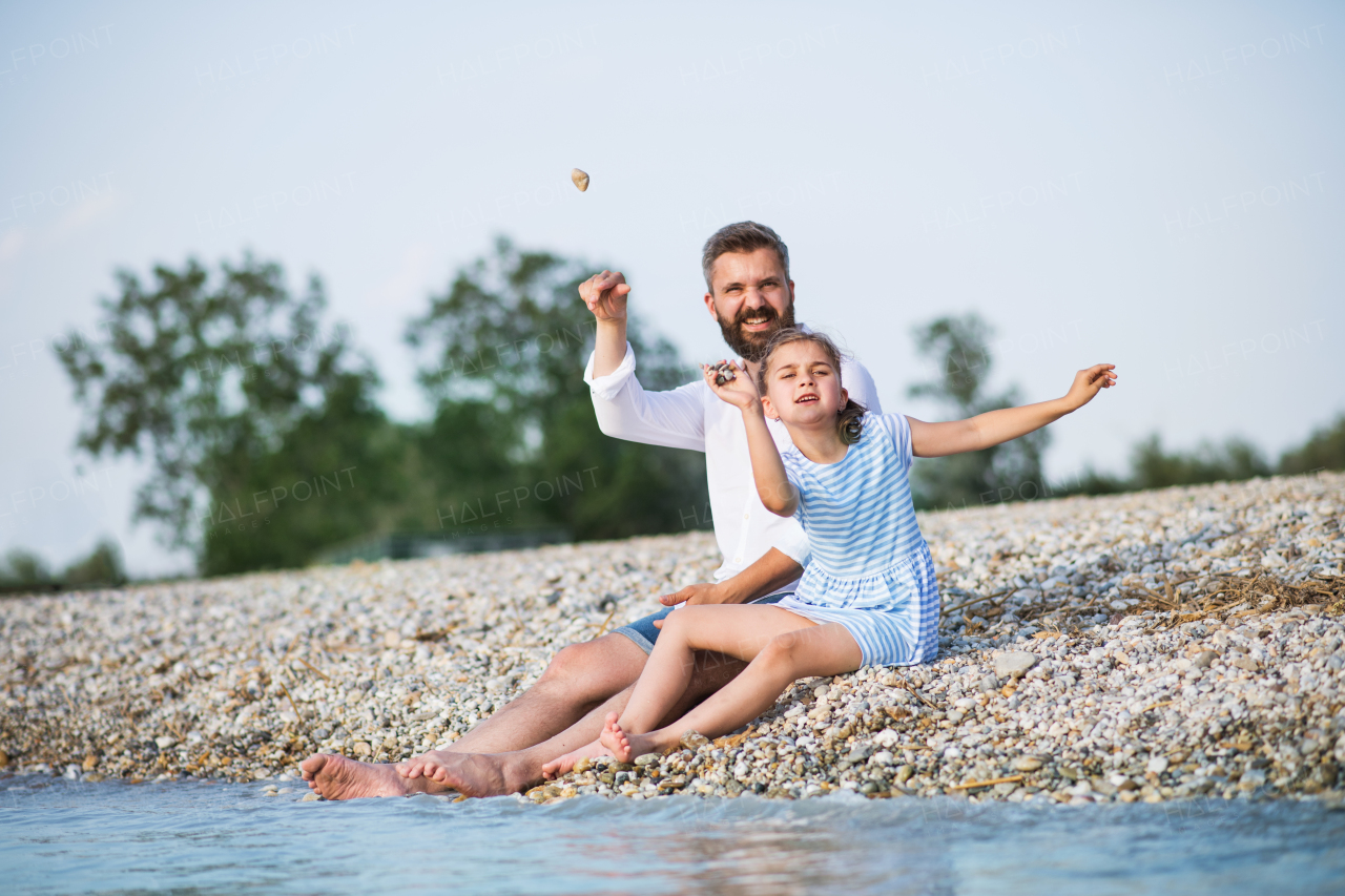 Father and small daughter on a holiday sitting by the lake or sea.