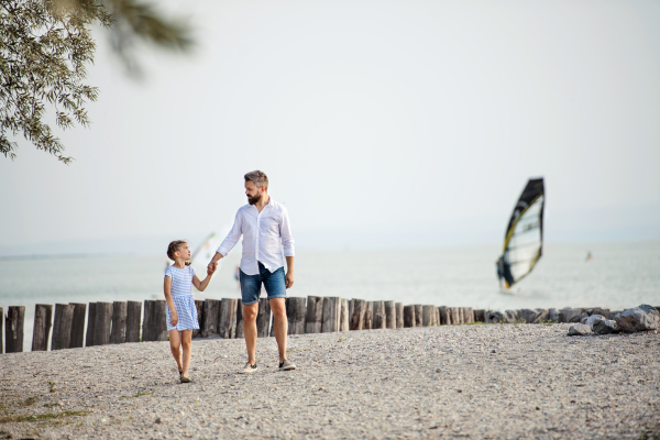 A mature father and small daughter on a holiday walking by the lake or sea.