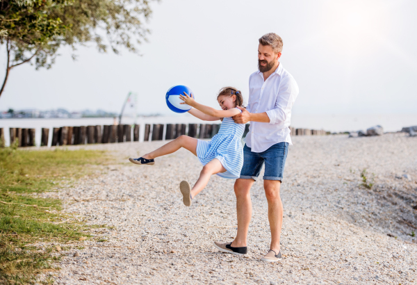 A mature father and small daughter on a holiday playing by the lake or sea.