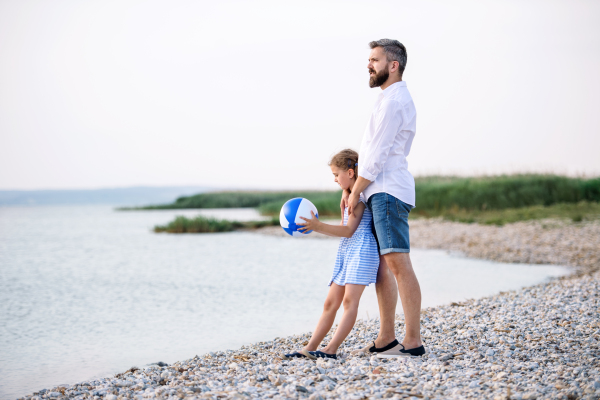 A mature father and small daughter on a holiday playing by the lake or sea.