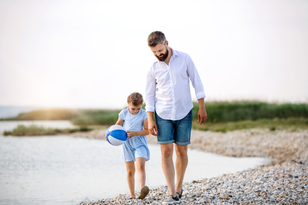 A mature father and small daughter on a holiday walking by the lake or sea.